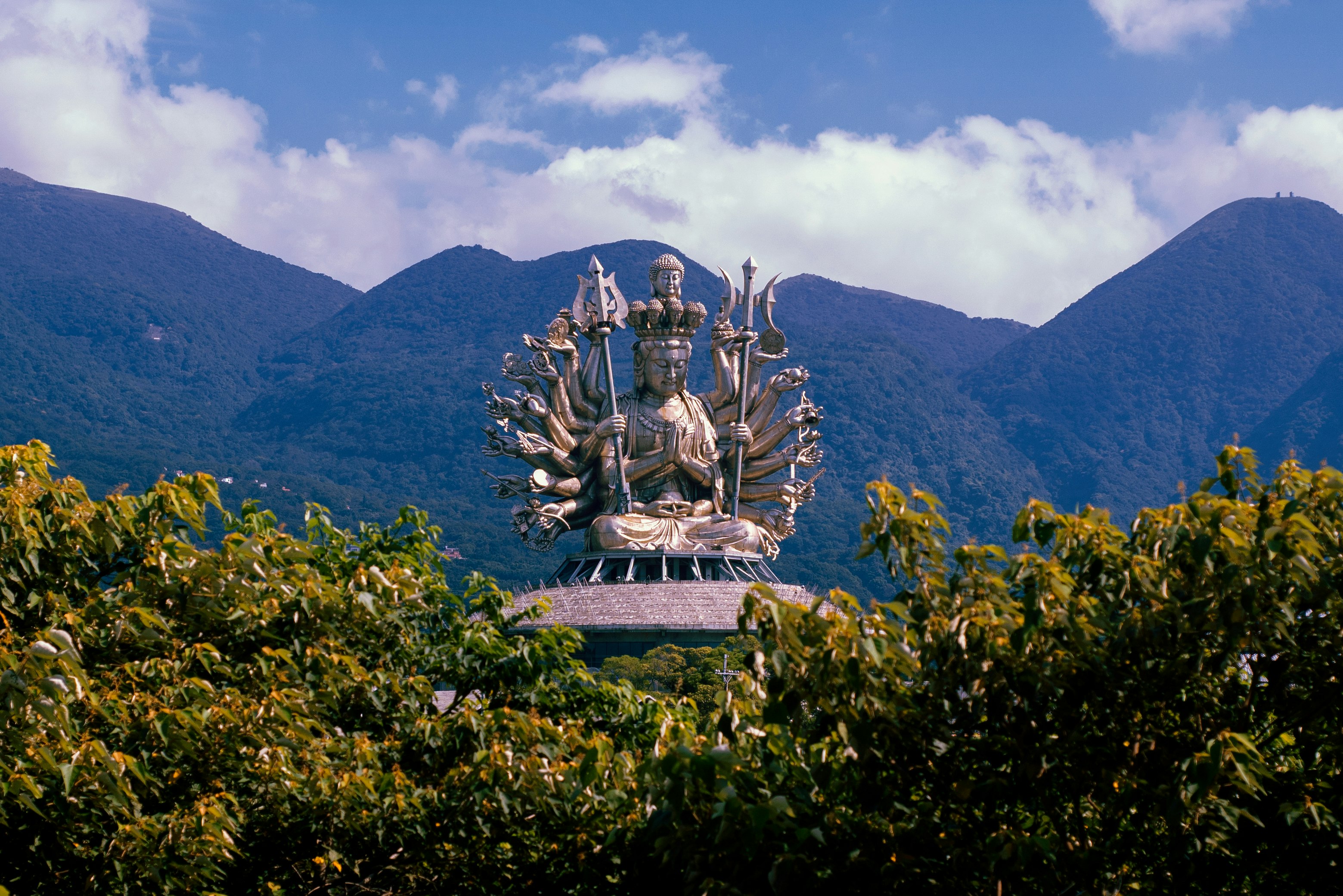 white concrete statue on green grass field near mountain under blue sky during daytime